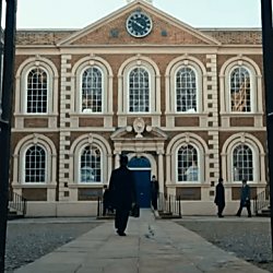 A man walking towards The Bluecoat building with some people standing by the entrance.