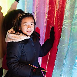A young girl inside a colourful inflatable artwork touching the work