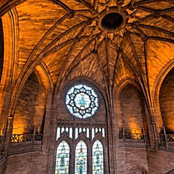 Inside the Liverpool Cathedral. A grand vaulted ceiling and stained glass windowas.