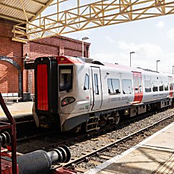 a train pulled into a station. The train has red and grey colours on it.