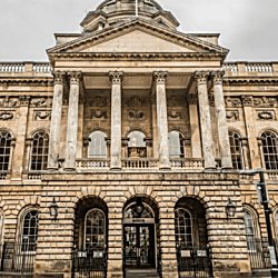 The exterior of Liverpool Town Hall with six pillars on the front and three arches above windows.