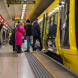 An image of the Merseyrail train with people waiting to board it.
