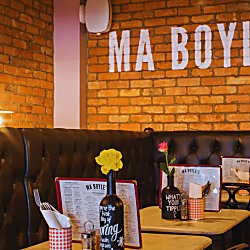 Inside Ma Boyle's an old traditional pub, with exposed brick walls, leather chairs and wooden tables with flowers in bottles.
