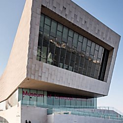 Exterior of Liverpool Museum - a modern brutalist style building made from white blocks and a large glass window