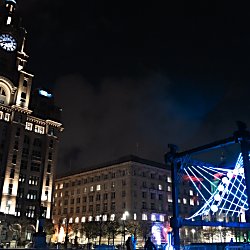 A large light installation that looks like a large pendulum outside of the Royal Liver Building.