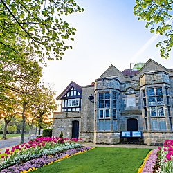 Outside of Port Sunlight museum with flowers in the front and a sunset in the background.