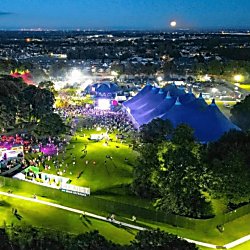 An evening festival scene with big top tents and crowds