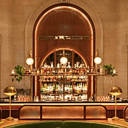 A portrait shot of an art deco interior bar with a large vaulted ceiling with red and green details.