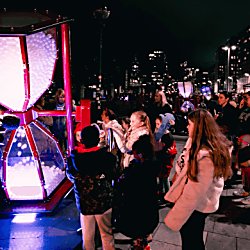 LAPS installation lit up with kids playing on the installation. It's a dark night and the installation is lit up purple.