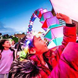 A young girl touches a colourful art installation at River of Light 2022