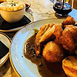 A side view of a plate with a roast dinner on including an extra side of potatoes and mash and a glass of red wine