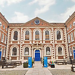 The Bluecoat building exterior with the clock centrally located above the blue door. The sky is blue and there is no one around the building.