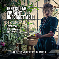A woman wearing a period drama dress with hair loosely tied up. There's plants around her with wooden baskets.