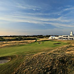 The Royal Birkdale golf club at the end of a gold course with green grass and grassy bunkers.