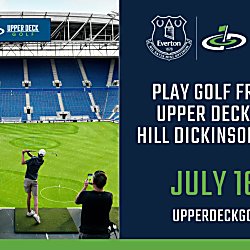 Promotional graphic showing a golf experience inside a large football stadium with rows of blue seats and a bright green pitch marked with circular golf targets. In the foreground, several people stand on a raised platform hitting golf balls toward the field while one person records on a phone. A banner above the seating reads “Upper Deck Golf.” On the right side, a navy panel displays the Everton crest alongside the Upper Deck Golf logo and text reading: “Play golf from the upper deck inside Hill Dickinson Stadium. July 16–19. upperdeckgolf.com.”