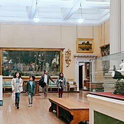 A family of four inside the Lady Lever Museum looking at paintings and sculptures around the gallery space.
