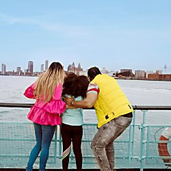 A family with a young girl in between them both look across the River Mersey
