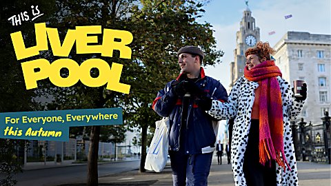 Two people walking infront of the Royal Liver Building wearing winter clothing. The text says This is Liverpool in yellow text.