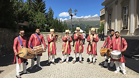 A group of men with drums and brass instruments wearing traditional Indian clothing