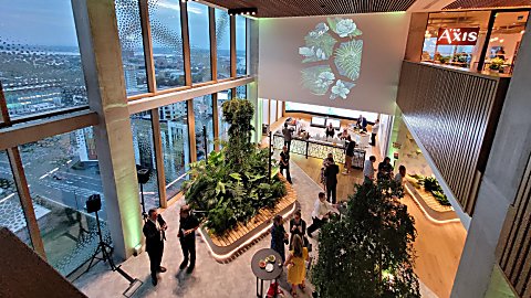Event space in Spaces at The Spine with a lot of plants, green uplighters and a screen with a projection on it.