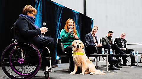 panellists sit on a stage at the accessibility forum