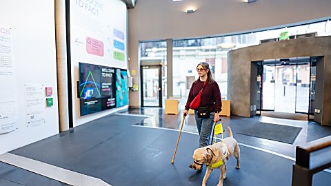 A person walking with a guide dog in a venue.