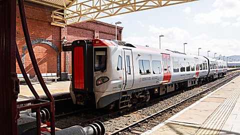 a train pulled into a station. The train has red and grey colours on it.