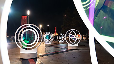 Light installations in circles that spin around with lights in the middle of it.