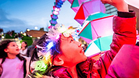 A young girl touches a colourful art installation at River of Light 2022