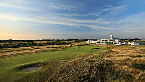 The Royal Birkdale golf club at the end of a gold course with green grass and grassy bunkers.