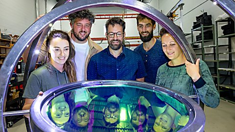 A group of people standing looking at an artwork for River of Light.