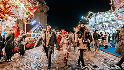 A family of three with two adults and a child at the Liverpool Christmas markets.