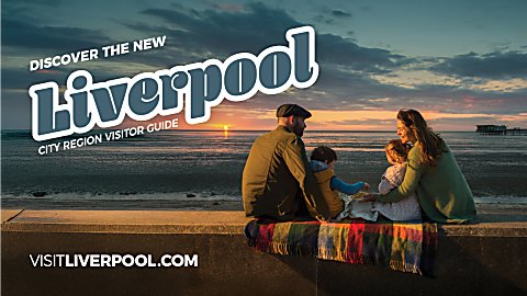 A family sitting together with the sun setting in the distance. There is a pier to the right of the image.