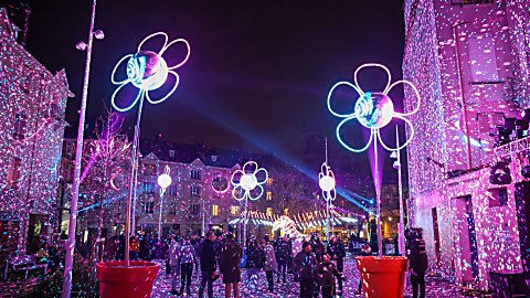 Colourful pink lighting projected onto walls with large light artworks in the shape of flowers in pots dotted around.