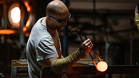 A person making glass in a workshop.