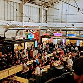Inside a warehouse food market with festoon lighting and bench seating