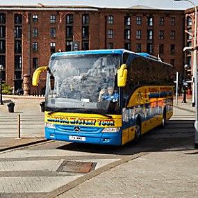 The 'Magical Mystery Tour' coach on Liverpool Albert Dock. The coach is bright yellow and green with rainbow writing on the side