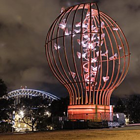 A large light sculpture which looks like a light blub with moths flying around it.