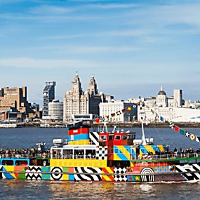 The Mersey Ferry covered in colourful patterns sailing on the Mersey Ferry with the Liverpool skyline in the background