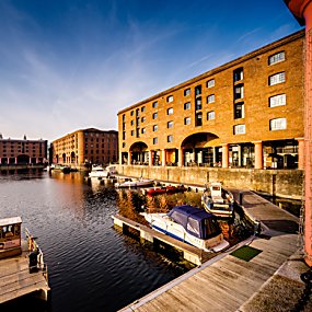 The Royal Albert Dock Warehouse buildings at golden hour. The old warehouse buildings have archways, small windows and large red columns.