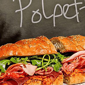 A large sandwich with different meat on it on a plate.