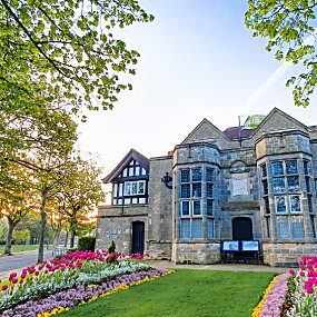 Outside of Port Sunlight museum with flowers in the front and a sunset in the background.
