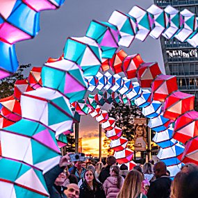 Accordion shaped archways in lots of colours, lit up with people walking through them