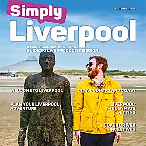 An image of a man standing beside the Anthony Gormley statue, laughing and looking happy.