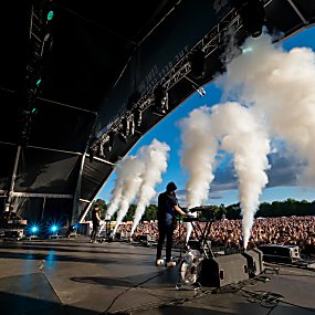 A man stands on stage with smoke canons