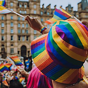 A person wearing a pride rainbow hat in a crowd of people at st George's Plateau where the march is about to begin.