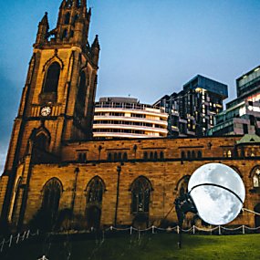An old church building with a moon being 'lassoed' outside