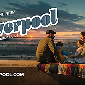 A family sitting together with the sun setting in the distance. There is a pier to the right of the image.