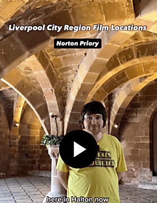 A person wearing a yellow t shirt inside a room with brick vaulted ceilings and archways.