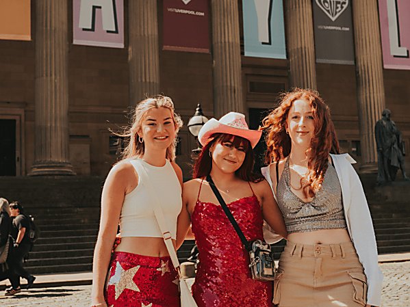 3 girls dressed for Taylor Swift stand outside St Georges Hall during golden hour